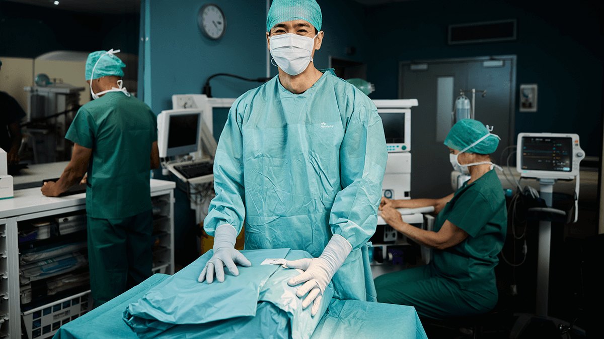 Mölnlycke ProcedurePak Custom Procedure Trays for the Operating Room 3 Theatre nurse in gown setting out ProcedurePak tray contents on a draped trolley in an operating room