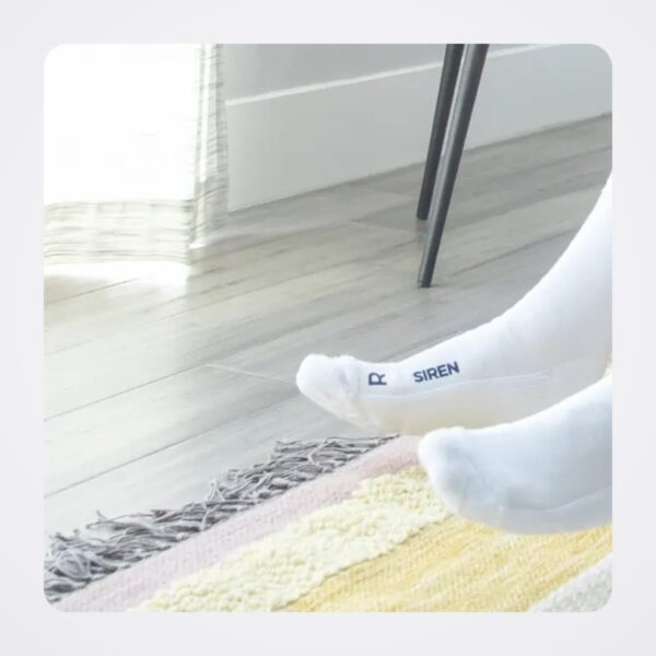 Pair of white Siren Socks with Siren branding on the cuff, worn on the feet