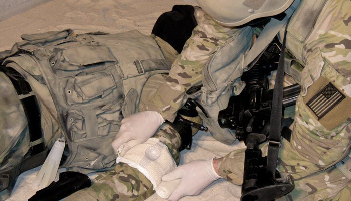 TacMed Solutions OLAES Modular Bandage Trauma Dressing 5 Medic applying an OLAES Modular Bandage with pressure cup to a soldier's arm